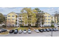 A yellow condominium building with white balconies overlooks the parking lot on a sunny day at 601 N Hillside Dr. # 2235, North Myrtle Beach, SC 29582