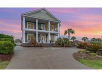 Two-story home with white columns, green siding, and lush landscaping provides tons of curb appeal at 898 Bluffview Dr., Myrtle Beach, SC 29579