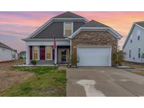 Charming two-story home featuring a stone accent wall, two car garage, and an American flag at 909 Witherbee Way, Little River, SC 29566