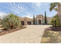 Stately home featuring arched entry, meticulous landscaping, a paver drive, and a two-car garage in a warm, inviting color palette at 9200 Bellasera Circle, Myrtle Beach, SC 29579