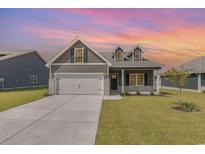 Charming two-story home boasts gray siding, dormer windows, a two-car garage, and a well-manicured lawn at 127 Old Chimney Ln, Conway, SC 29526