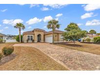 Charming single-story home with a brick driveway, a two-car garage, and mature landscaping at 169 Northside Dr., Little River, SC 29566