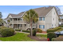 Inviting two-story condo with charming exterior, blue shutters, a lush lawn, and attractive landscaping at 1870 Auburn Ln. # 21C, Surfside Beach, SC 29575