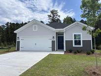 Charming single-story home featuring a two-car garage, manicured lawn, and welcoming blue front door at 264 Palmetto Sand Loop, Conway, SC 29527