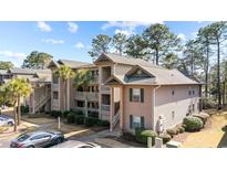A beautiful condo with a neutral exterior, complimented by lush landscaping and palm trees against a blue sky at 270 Pinehurst Ln. # 9G, Pawleys Island, SC 29585