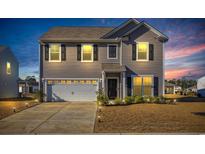 Charming two-story home featuring a 2-car garage, manicured lawn, and inviting curb appeal during twilight hours at 3032 Red Bark Dr., Conway, SC 29526