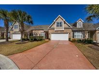 Charming brick townhome with a two-car garage, well-manicured lawn, and a vibrant, reddish-brown driveway at 517 Poppi Point Ct. # 517, Myrtle Beach, SC 29579