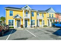 View of a yellow condo building with parking in front and well maintained landscaping under a bright blue sky at 753 Moen Pl. # B, Myrtle Beach, SC 29577