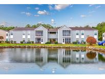 Exterior view of condo building with a tranquil pond and lush landscaping reflecting on the water at 8861 Cloister Dr. # F, Surfside Beach, SC 29575