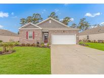Charming single-story brick home with manicured lawn and two-car garage under a bright, sunny sky at 1119 Maxwell Dr., Little River, SC 29566