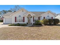 Charming home with white siding, red shutters, beautiful landscaping, and an inviting front porch entrance at 2029 Hawksmoor Dr., Conway, SC 29526