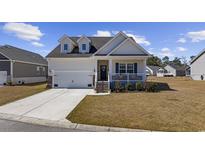 Charming home featuring a welcoming front porch, attached garage, and well-manicured lawn on a sunny day at 517 Antebellum Ln., Georgetown, SC 29440