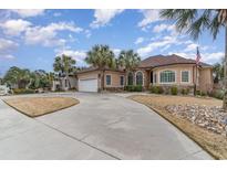 Elegant stucco home featuring palm trees, a circular driveway, and a two-car garage at 601 Tradewind Ct., North Myrtle Beach, SC 29582