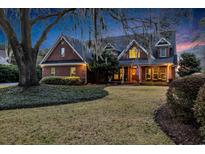 Charming brick home featuring a manicured front lawn and mature landscaping with inviting front porch at 626 Heritage Dr., Pawleys Island, SC 29585