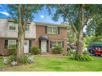Brick townhome featuring a well-manicured lawn, mature trees, and classic architecture at 7100 Porcher Dr. # A, Myrtle Beach, SC 29572