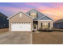 Charming home featuring mixed siding, an attached two-car garage, and tasteful landscaping against a colorful sky at 713 Lambeth Ln., Conway, SC 29526