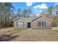 Charming brick home featuring a well-maintained lawn and dark shutters beneath a partly cloudy sky at 1580 Circle Bay Dr., Longs, SC 29568