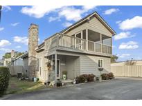 Two-story home with a charming balcony, screened porch, brick chimney, and attractive landscaping at 1710-C Edge Dr., North Myrtle Beach, SC 29582