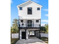 Stunning three-story home with modern black and white design, covered parking, and a charming front porch at 316B Lakeside Dr., Surfside Beach, SC 29575