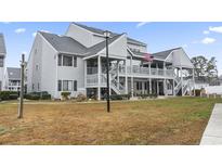 Two-story condo with a charming deck, gray siding, an American flag, and well-maintained landscaping at 1880 Auburn Ln. # 24E, Surfside Beach, SC 29575