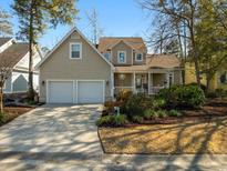 Charming tan two-story home features a two-car garage, inviting front porch and well-manicured landscaping at 4966 S Island Dr. S, North Myrtle Beach, SC 29582