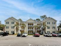 Well-maintained three-story building with palm trees and ample parking under a blue sky at 601 Hillside Dr. N # 4535, North Myrtle Beach, SC 29582