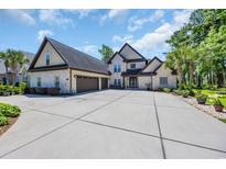 Stately brick home featuring a spacious driveway and a well-manicured lawn and three car garage at 9785 Anchor Dr., Longs, SC 29568