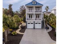 Stunning two-story coastal home with a blue roof and multi-level balconies overlooking the lush landscaping at 110 Grackle Ln., Pawleys Island, SC 29585