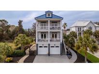 Three-story coastal home with white balconies, blue metal roof, and two-car garage at 110 Grackle Ln., Pawleys Island, SC 29585