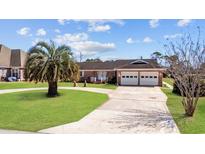 Charming brick home features a well-manicured lawn, palm tree, and a spacious driveway leading to a two-car garage at 1463 Gibson Ave., Surfside Beach, SC 29575