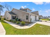Charming townhouse boasts a well-maintained lawn, lush landscaping, and attached garages at 1586 Jardine Loop, Little River, SC 29566