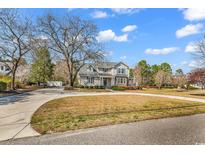 Charming two-story home featuring a well-manicured lawn, mature trees, and a welcoming front porch on a sunny day at 182 Duck Blind Trail, Myrtle Beach, SC 29588