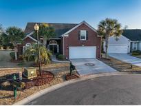 Charming brick home featuring a well-manicured lawn, palm trees, and a two-car garage at 3901 Bay Pines Ct., North Myrtle Beach, SC 29582
