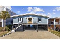 Charming coastal home with a blue exterior, black shutters, and a spacious drive-under garage at 414 S Dogwood Dr., Garden City Beach, SC 29576