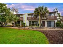 Charming two-story condo featuring brown trim and landscaping with mature palm trees at 415 Queens Rd. # B, Myrtle Beach, SC 29572