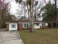 Charming ranch-style home featuring a brick facade, blue shutters, a well-manicured lawn, and mature trees at 4300 Crows Nest Ct., Myrtle Beach, SC 29579