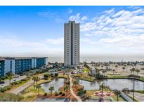 Scenic aerial view featuring a high-rise condo building, pond, parking, and partial ocean views on a partly cloudy day at 5905 S Kings Hwy. # 810-C, Myrtle Beach, SC 29575