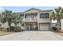 Charming raised beach house featuring a spacious driveway, palm trees and a cozy covered porch and an under-house entertainment area at 619 10Th Ave. S, North Myrtle Beach, SC 29582