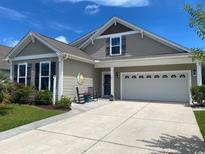 Charming home exterior with neutral siding, rocking chairs on the porch, and a two-car garage at 808 Yauhannah Dr., Little River, SC 29566