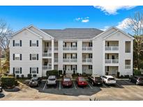 A view of the condo's exterior with white siding and parking in front under a blue sky at 901 West Port Dr. # 1611, North Myrtle Beach, SC 29582