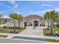 Stucco home featuring an arched double-door entryway, brick drive, meticulous landscaping, and palm trees at 1012 Dowitcher Dr., Conway, SC 29526