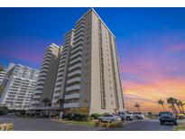 A large condominium building with a parking lot and lovely landscaping at sunset at 10200 Beach Club Dr. # 6B, Myrtle Beach, SC 29572