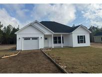 Charming single-story home featuring white siding, black shutters, and an attached garage, set against a blue sky at 10534 W Highway 19, Loris, SC 29569