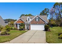 Charming brick home featuring a well-manicured lawn and attached two-car garage at 1205 Woodruff Ct., Conway, SC 29526