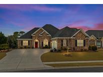 Charming brick home featuring a red door, manicured lawn, and a welcoming curb appeal at 205 Deep Blue Dr., Myrtle Beach, SC 29579