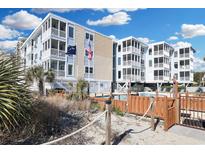 Exterior view of a light blue condo building and pool with ocean views and American and South Carolina flags at 2405 S Ocean Blvd. # 105, North Myrtle Beach, SC 29582