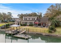 Stunning waterfront home featuring a private dock, manicured lawn, and outdoor seating area at 288 Rum Gully Rd., Murrells Inlet, SC 29576