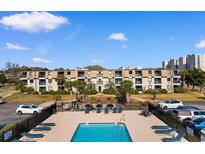 Well-maintained condo complex with a swimming pool and palm trees, offering a resort-like atmosphere at 405 21St Ave. S # 2H, North Myrtle Beach, SC 29582