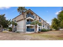 Coastal condo building with blue railings on balconies and palm trees in a landscaped yard under a bright sky at 405 21St Ave. S # 2H, North Myrtle Beach, SC 29582