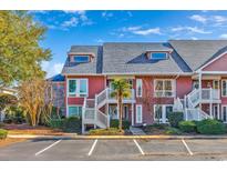 Charming townhome with a red exterior, white trim, well-kept landscaping, and a dedicated parking area at 4760 Lightkeepers Way # 20-A, Little River, SC 29566